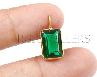 May include: A gold pendant with a large, emerald green rectangular gemstone.
