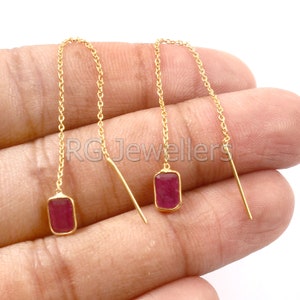 May include: A pair of gold chain earrings with red rectangular gemstones. The earrings are dangling and have a simple design.