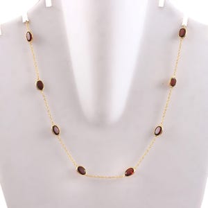 May include: A gold chain necklace with oval-shaped red gemstones.