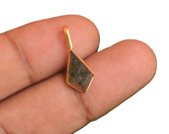 May include: A kite-shaped pendant featuring a translucent, dark green gemstone set in a polished gold-toned metal frame. The pendant includes a small, rectangular gold-toned bail at the top for attachment to a chain or cord, showcasing a simple design.
