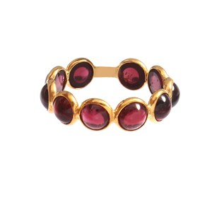 Könnte beinhalten: Ein goldener Ring mit einer Reihe von runden, tiefroten Edelsteinen. Die Edelsteine sind in einzelnen Goldfassungen gefasst, wodurch ein durchgehendes Farbband entsteht. Das Design des Rings ist schlicht und elegant, mit Fokus auf der satten Farbe der Steine.