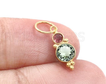 May include: Gold charm with a green and light green gemstone, a pink gemstone, and gold beads.