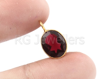 Puede incluir: Un colgante de oro con una piedra preciosa de color rojo oscuro grande y ovalada.