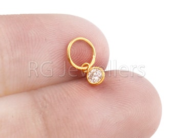 May include: A gold nose ring with a small, clear gemstone pendant.