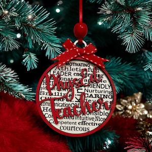 May include: Red and white Christmas ornament with the words "Phys Ed Teacher" in a large, bold font. The ornament is surrounded by smaller words describing positive qualities, such as "motivating", "caring", and "effective".
