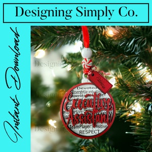 Könnte beinhalten: Ein roter und weißer Weihnachtsbaumschmuck mit den Worten "Executive Assistant" umgeben von anderen positiven Wörtern wie "engagiert", "energisch", "intuitiv", "unterstützend", "Teamplayer", "sensibel" und "Respekt". Der Schmuck hängt an einem Weihnachtsbaum.