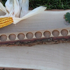 May include: A wooden tray with 12 round holes, perfect for holding small items. The tray is made from a natural piece of wood with a bark edge.