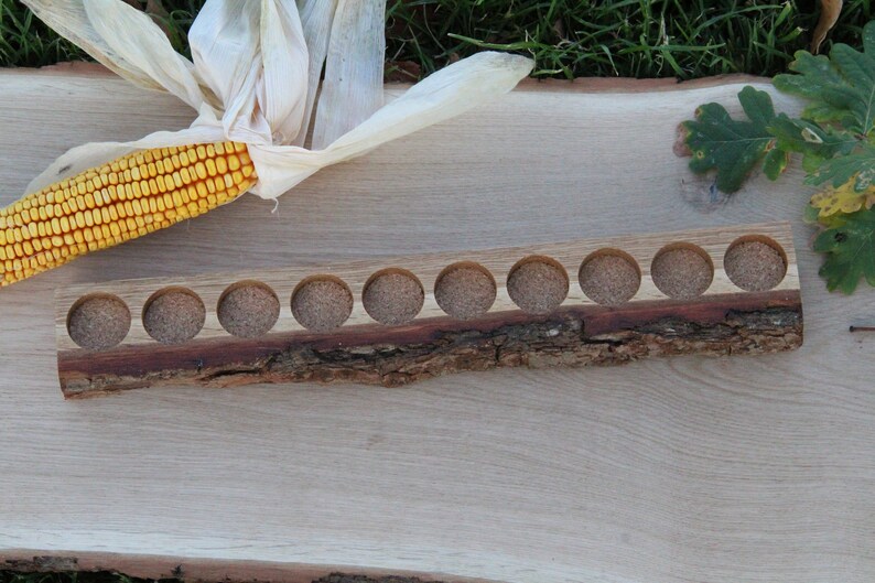 May include: A wooden tray with 12 round holes, perfect for holding small items. The tray is made from a natural piece of wood with a bark edge.