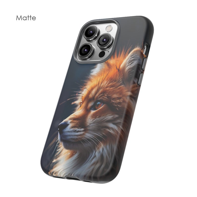 以下が含まれることがあります： 赤いキツネの顔のクローズアップ画像がプリントされた黒い携帯電話ケース。キツネは画像の左を見ています。ケースはマット仕上げです。