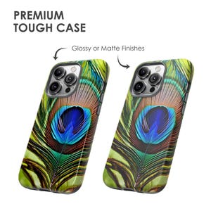 K&ouml;nnte beinhalten: Zwei Handyh&uuml;llen mit einem Pfauenfeder-Design. Die H&uuml;llen sind in gl&auml;nzender oder matter Ausf&uuml;hrung erh&auml;ltlich. Die Handyh&uuml;llen sind f&uuml;r das iPhone 13 Pro konzipiert.