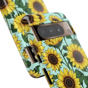 May include: A turquoise phone case with a sunflower pattern. The case has a gold trim and a camera lens cutout.