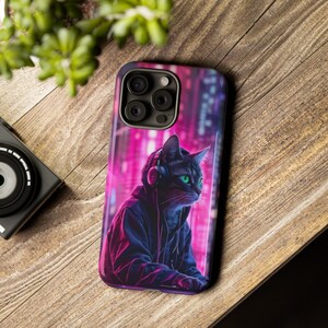 May include: A black cat wearing headphones and a hoodie, with a neon pink and blue city background. The cat is looking to the right. The image is on a phone case.