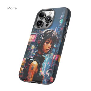 May include: A black phone case with a matte finish featuring a colourful illustration of a woman with headphones in a futuristic cityscape.
