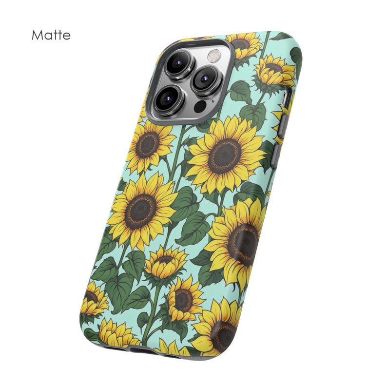 May include: A matte black phone case with a sunflower pattern on a light blue background. The case has a cutout for the camera lens.