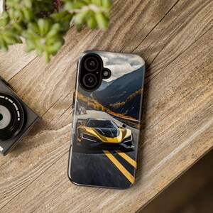 Puede incluir: Un coche deportivo amarillo con detalles negros circula por una carretera sinuosa a trav&eacute;s de un paso de monta&ntilde;a. El coche aparece en una funda de tel&eacute;fono con fondo negro.