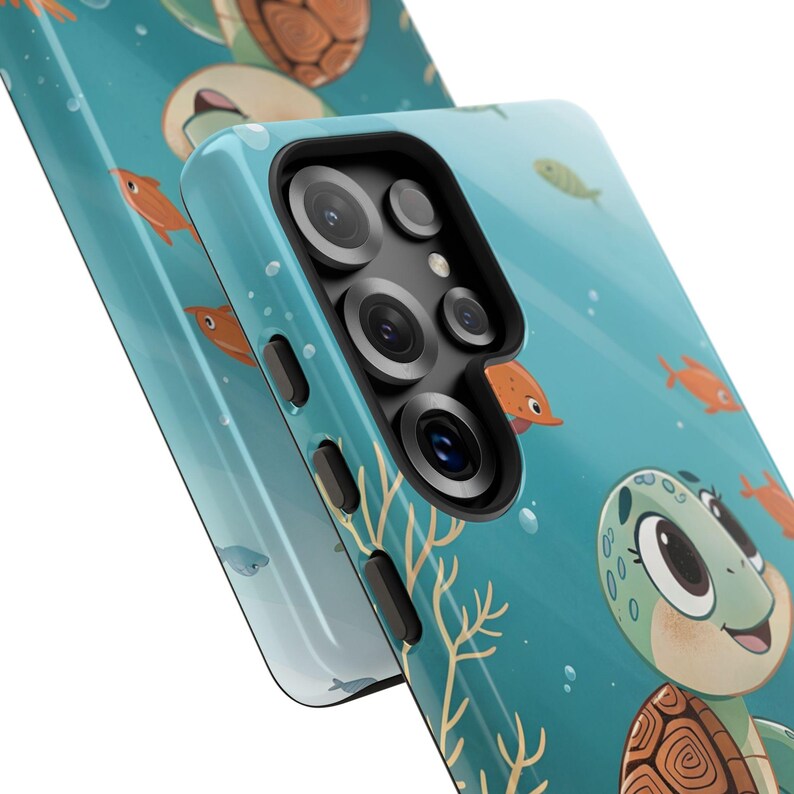 Może przedstawiać: Turkusowe etui na telefon z kresk&oacute;wkowym wzorem ż&oacute;łwia, pomarańczowymi rybami i koralowcami na niebieskim tle. Etui ma błyszczące wykończenie i wycięcie na aparat. Projekt zawiera bąbelki i przyjaznego ż&oacute;łwia.