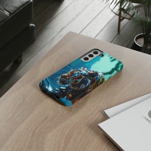 Puede incluir: Una funda de tel&eacute;fono negra con una imagen azul y verde de un tigre con ojos brillantes. El tigre est&aacute; rodeado de un fondo azul y verde.