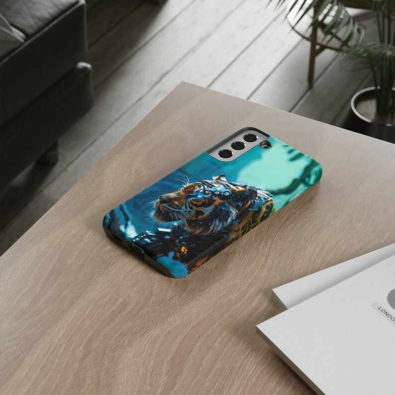 Puede incluir: Una funda de tel&eacute;fono negra con una imagen azul y verde de un tigre con ojos brillantes. El tigre est&aacute; rodeado de un fondo azul y verde.