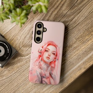 May include: A pink phone case with a colorful illustration of a woman with pink hair wearing headphones. The case has a black camera cutout with three lenses.