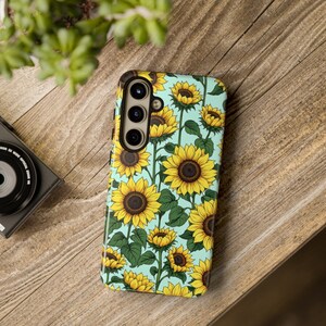 May include: A turquoise phone case with a sunflower pattern. The case has a cutout for a triple lens camera.