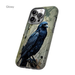May include: A phone case with a glossy finish featuring a raven perched on a branch with a green, brown, and white abstract background. The case has a camera cutout with three lenses.