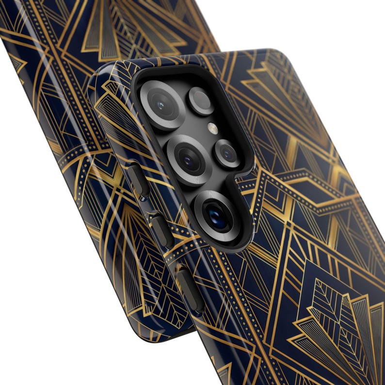 May include: Two navy blue phone cases with a gold Art Deco pattern. The phone case on the right has a camera bump with multiple lenses and buttons on the side. The design is a repeating geometric pattern.