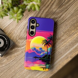 May include: A purple phone case featuring a sunset and palm tree design. The case has a yellow sun, pink and blue clouds, and a green palm tree.