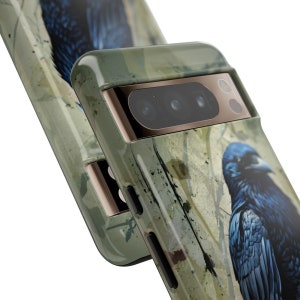 May include: A green, black, and gold phone case with a raven design. The case has a camera lens cover with three lenses.