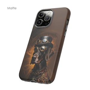 May include: A brown and black phone case featuring a steampunk-style illustration of a dog wearing goggles and a top hat. The case has a matte finish and a camera cutout.
