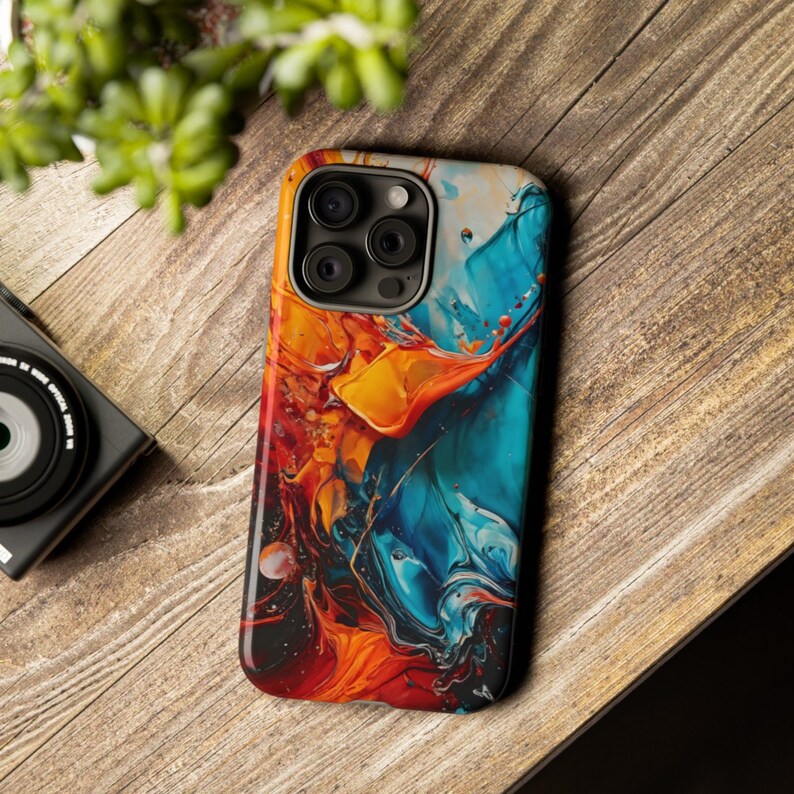 Puede incluir: Una funda para tel&eacute;fono con un dise&ntilde;o abstracto colorido que presenta remolinos de pintura azul, naranja y roja. La funda tiene un recorte para la c&aacute;mara del tel&eacute;fono.