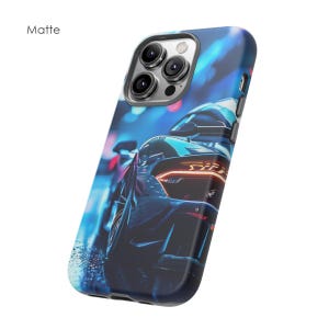 May include: A blue and black phone case with a matte finish. The case features a photo of a sports car with its headlights on. The case has a cutout for the camera lens.