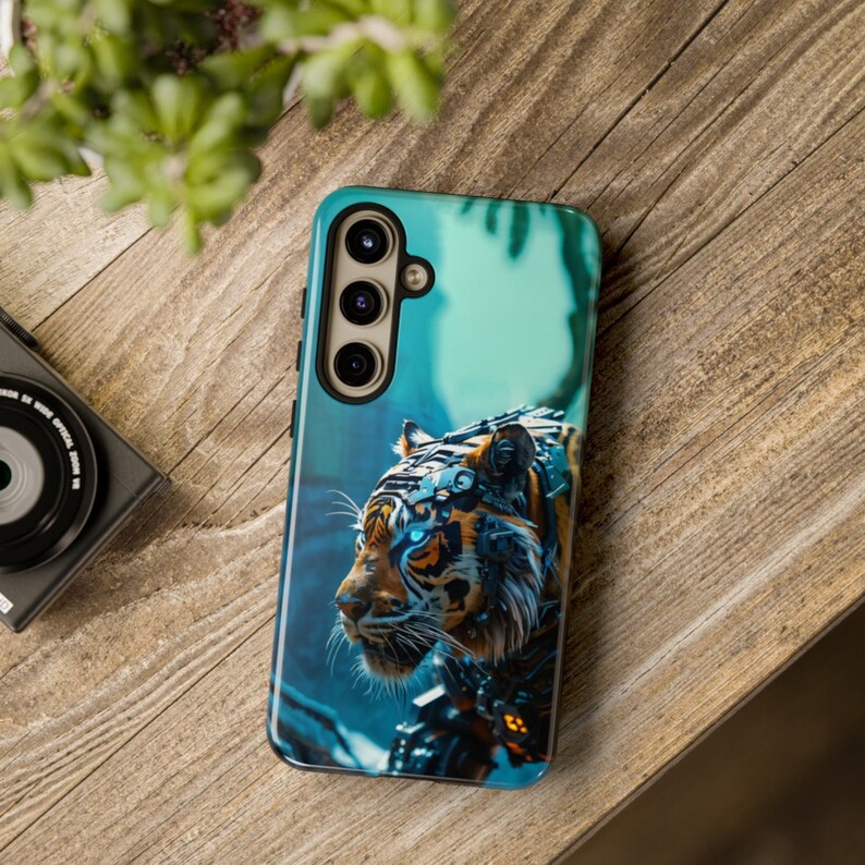 Puede incluir: Una funda de tel&eacute;fono azul y negra con un gr&aacute;fico de un tigre rob&oacute;tico con ojos azules brillantes. La funda tiene un recorte para la c&aacute;mara del tel&eacute;fono.