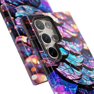 Op de afbeelding: Een telefoonhoesje met een kleurrijk, iriserend patroon dat lijkt op vissen schubben. Het hoesje heeft een zwarte camera-uitstulping met drie lenzen.