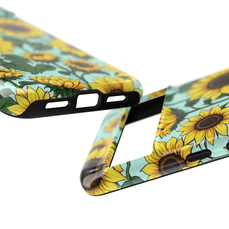 May include: A phone case with a sunflower pattern on a light blue background. The case has a black bumper and a cutout for the camera lens.