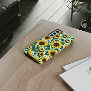 May include: A turquoise phone case with a sunflower pattern. The case is designed for a smartphone with a camera bump.