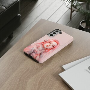 May include: A pink phone case with a design of a woman with pink hair. The case has a cutout for the camera lens.
