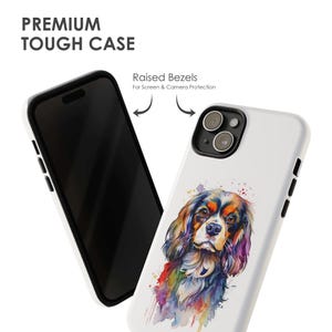 May include: A white phone case featuring a colourful watercolour illustration of a Cavalier King Charles Spaniel dog. The case has raised bezels for screen and camera protection. "Raised Bezels For Screen & Camera Protection" text is printed on the case.