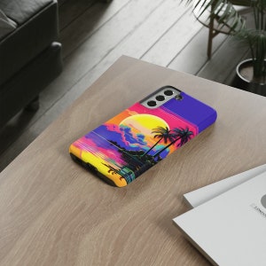 May include: A black phone case featuring a colourful sunset and palm trees graphic. The case has a cut-out for the camera lens.