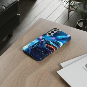 May include: A blue and black phone case featuring a graphic of a motorcycle rider in a neon cityscape. The case has a camera cutout with five holes.