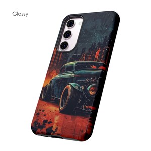 May include: A black phone case with a glossy finish features a vintage hot rod car driving through a city at night. The car is blue and green with red and orange highlights. The city skyline is in the background.