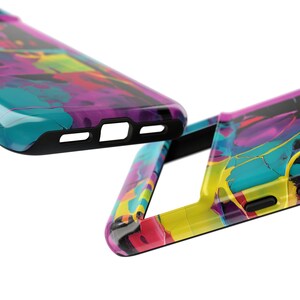 Op de afbeelding: Twee kleurrijke telefoonhoesjes met een marmerpatroon in tinten blauw, geel, roze en paars. De hoesjes zijn gemaakt van hard plastic en hebben een glanzende afwerking.