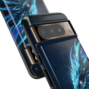 K&ouml;nnte beinhalten: Eine schwarze Handyh&uuml;lle mit einem blauen und wei&szlig;en Drachen-Design. Die H&uuml;lle hat einen goldenen Rand um das Kameraobjektiv.