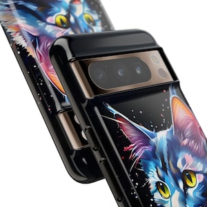 May include: A black phone case featuring a colourful cat design. The case has a camera lens cutout and a gold trim. The cat's eyes are bright yellow.