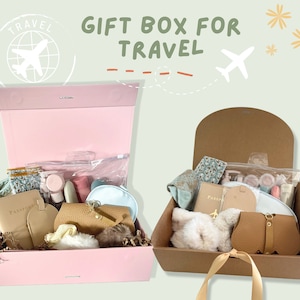 May include: Two gift boxes filled with travel-themed items. The pink box contains a passport holder, a small purse, a travel-sized toiletry bag, and other items. The brown box contains a passport holder, a small purse, a plush toy, and other items. Both boxes have a travel theme.