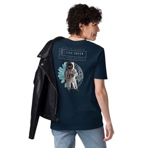May include: A navy blue t-shirt with a graphic of an astronaut standing in front of a blue and white flower. The text "LIVE GREEN" and "THE GREEN PROGRAM" is printed on the shirt.