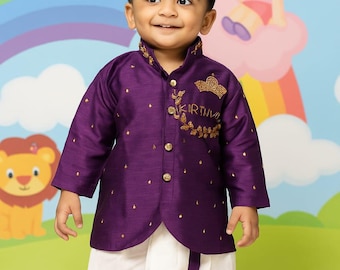 May include: A young child wearing a purple silk jacket with gold embroidery and a white dhoti. The jacket has the text "KIRTHIV" embroidered on it. The background features a rainbow and cartoon characters.
