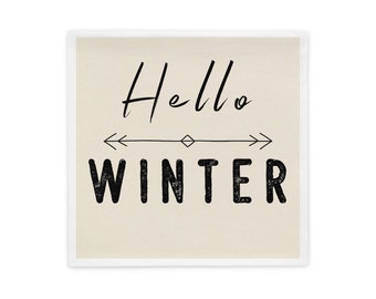 May include: Square pillow with a cream-colored background and the words "Hello WINTER" in black script and block letters. A black line with arrows and a diamond shape is between the words.