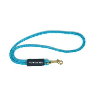 May include: A turquoise blue rope dog leash with a black tag that says "Your Name Here" and a gold metal clasp.