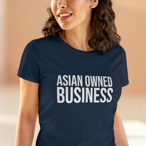 May include: A navy blue t-shirt with the text "ASIAN OWNED BUSINESS" printed in white on the front.