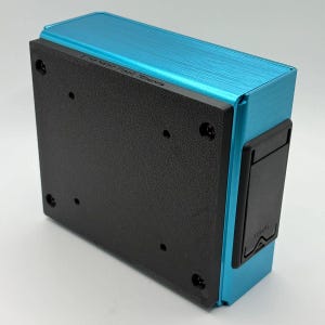 May include: A rectangular, teal-colored electronic device with a brushed metal finish. The device has a black, textured base and a black battery compartment door labeled "OPEN". The device is likely a piece of audio equipment or a similar electronic component.